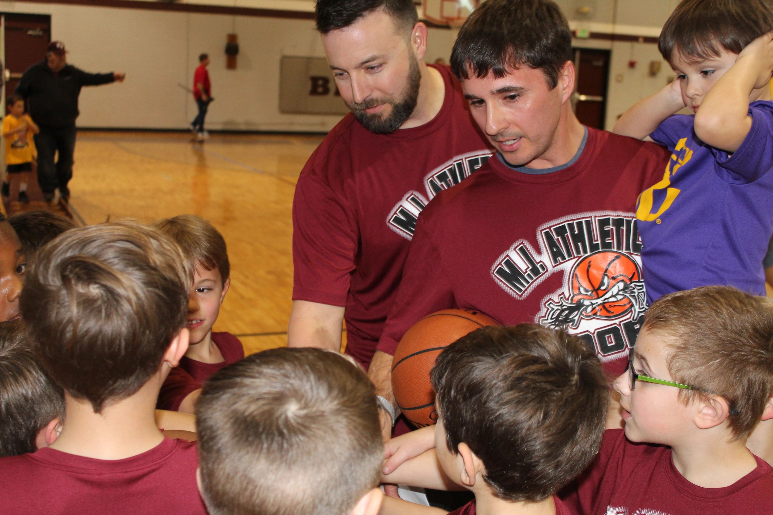 Coaches instructing young players around a basketball